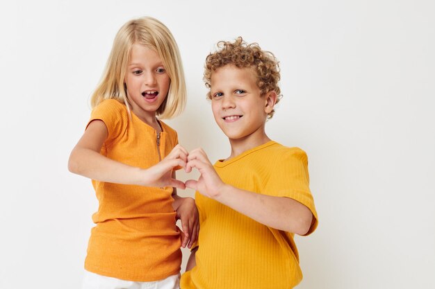 Joyeux garçon et fille en t-shirts jaunes posant en studio