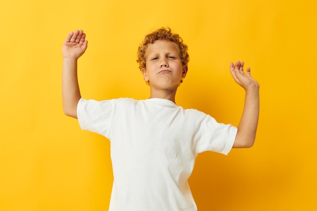 Joyeux garçon en t-shirt blanc posant studio fond jaune