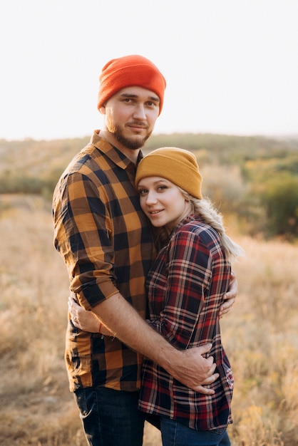 Joyeux gars et fille en promenade dans des chapeaux tricotés brillants et des chemises à carreaux