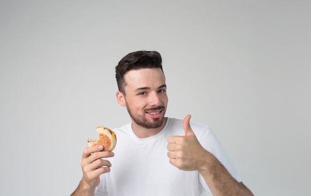 Joyeux gars positif tenir un morceau de burger à la main