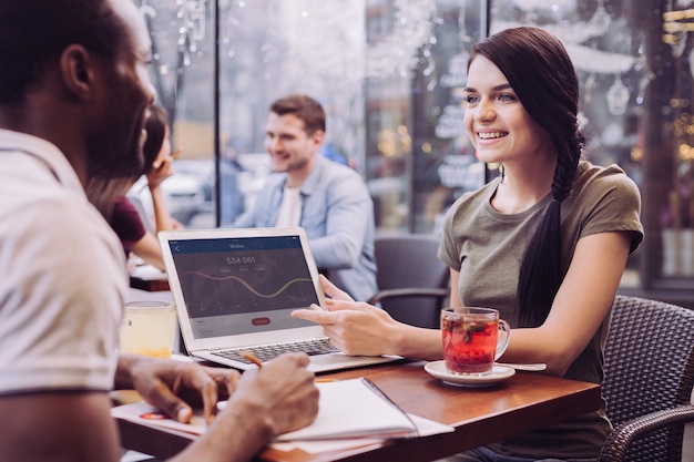 Joyeux gentil deux collègues débattant au café tandis que femme souriant et regardant l'homme