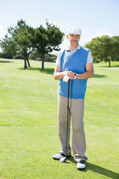 Joyeux golfeur souriant à la caméra tenant son club