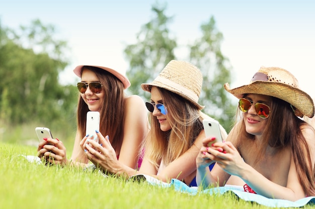 joyeux groupe d'amis allongés sur l'herbe et textos