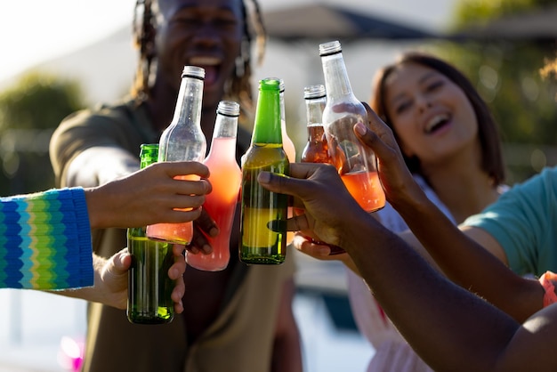 Joyeux groupe diversifié d'amis faisant la fête, buvant de la bière et portant un toast dans le jardin. Style de vie, amitié et fête, été, soleil, inchangés.