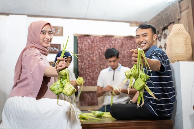 Joyeux groupe excité d'amis et de familles faisant du ketupat ensemble pour l'eid fitr mubarak ou la tradition idul fitri lebaran