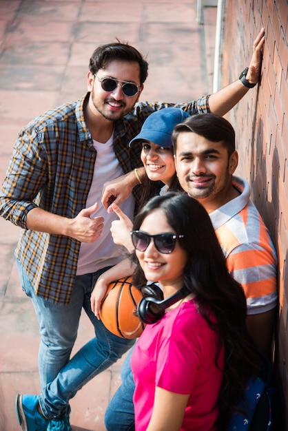 Joyeux groupe de jeunes asiatiques indiens d'étudiants ou d'amis riant ensemble assis, debout ou marchant sur le campus