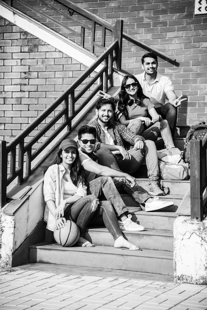 Joyeux groupe de jeunes asiatiques indiens d'étudiants ou d'amis riant ensemble assis, debout ou marchant sur le campus