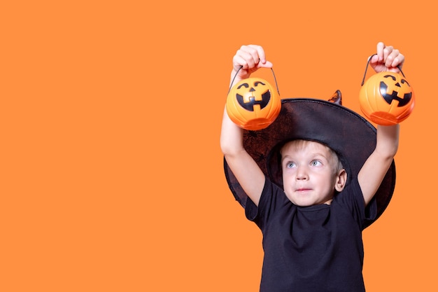 Joyeux Halloween. Enfants effrayants d'Halloween. Seaux de garçon effrayant joyeux avec des bonbons dans une lanterne citrouille pour halloween sur fond orange, espace de copie. Trick or Treat est une tradition d'Halloween.