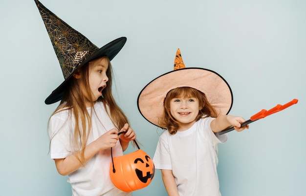 Joyeux Halloween Enfants avec un trident un panier en forme de citrouille et de chapeaux sur fond bleu avec espace de copie Préparation pour la fête d'Halloween