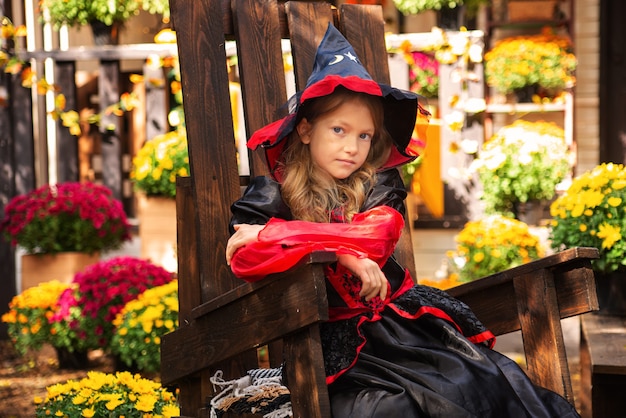 joyeux Halloween une fille en costume de sorcière avec une citrouille s'amusant à l'automne près de la maison