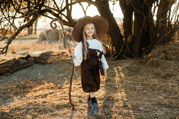 Joyeux Halloween. Une Jolie Fille En Costume De Sorcière Est Dans L'antre De La Sorcière. Jolie Petite Sorcière Gaie Prépare Une Potion Magique. Halloween.