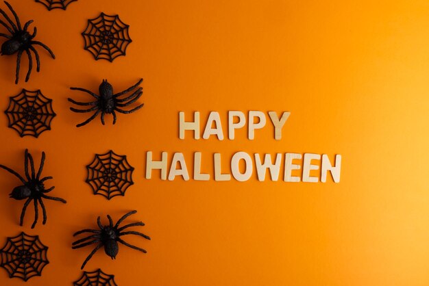 Joyeux Halloween lettrage sur fond orange avec halloween décor araignée et toile d'araignée