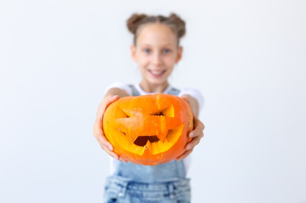 Joyeux Halloween, vacances d'automne et concept de l'enfance - Jolie petite fille avec un gros plan de citrouille Jack-o'-lantern