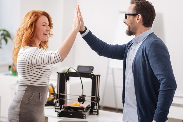 Joyeux et heureux collègues heureux qui se regardent et donnent un high five tout en terminant leur projet