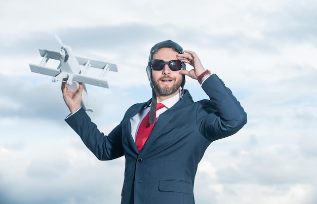 Joyeux homme d'affaires en costume et jouet d'avion de lancement de chapeau de pilote