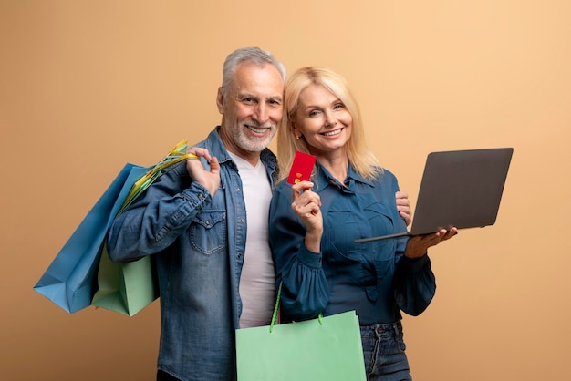 Joyeux homme âgé et femme faisant du shopping sur Internet à l'aide d'un ordinateur portable