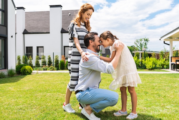 Joyeux homme agréable debout avec sa fille tout en lui montrant son amour