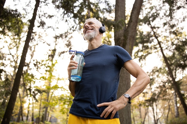 Joyeux homme athlétique faisant du jogging en forêt