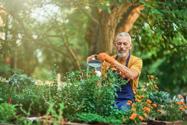 Joyeux homme caucasien d'âge moyen arrosant les plantes