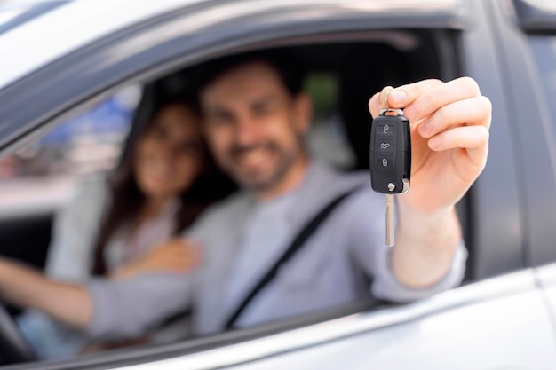 Joyeux homme et femme du millénaire achetant une nouvelle voiture montrant la clé