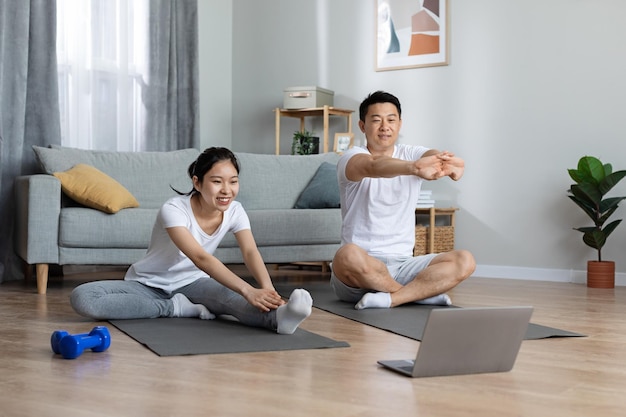 Joyeux homme et femme japonais en tenue de sport faisant de l'exercice à la maison