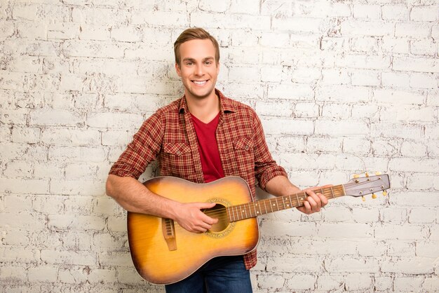 Joyeux homme heureux avec guitare sur le mur