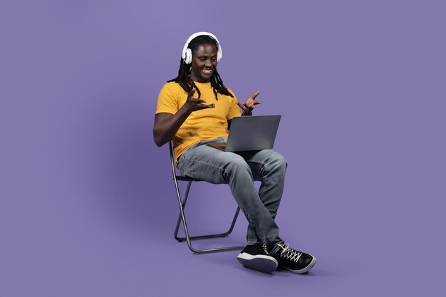 Joyeux homme noir à l'aide d'un ordinateur et d'un casque
