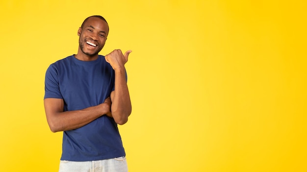 Joyeux homme noir pointant le pouce vers l'espace de copie sur fond jaune