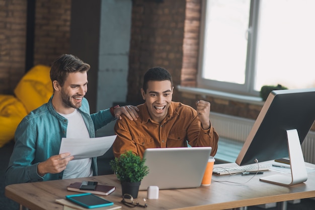 Joyeux hommes heureux montrant leurs émotions positives tout en atteignant un résultat réussi