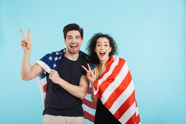 Joyeux jeune couple debout isolé, portant le drapeau américain