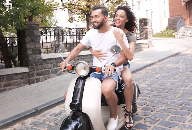 Joyeux jeune couple faisant du scooter et s'amusant