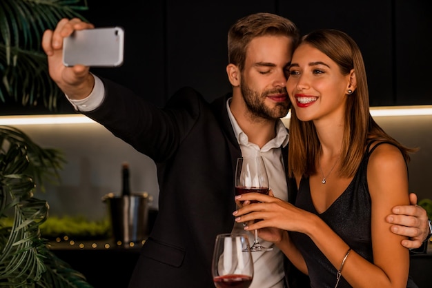 Joyeux jeune couple prenant selfie tout en dînant romantique à la maison