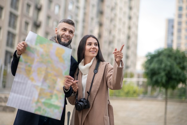 Joyeux jeune couple regardant autour tout en voyageant ensemble vers la nouvelle ville