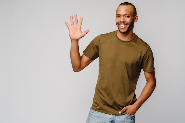 Joyeux jeune homme afro-américain amical en t-shirt vert montrant cinq avec les doigts