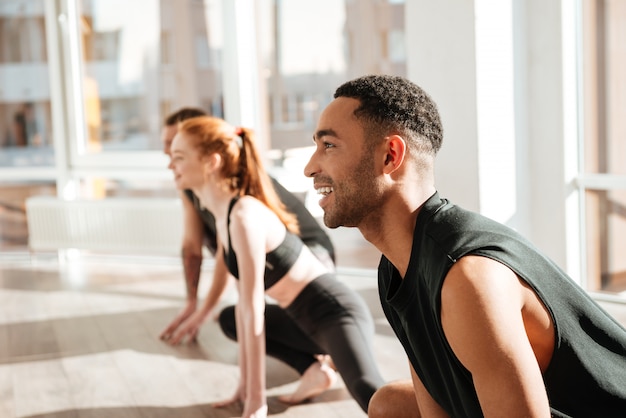 Joyeux jeune homme afro-américain, faire du yoga en groupe