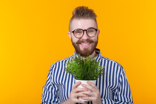 Joyeux jeune homme drôle tenant un pot avec des plantes