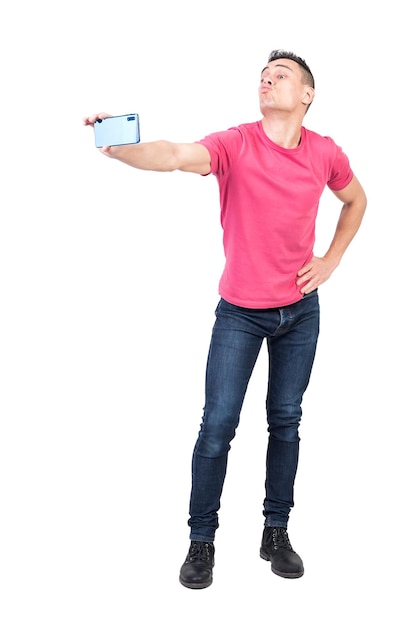 Joyeux jeune homme faisant la moue des lèvres et prenant selfie sur fond blanc