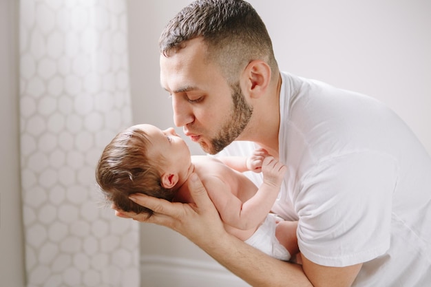 Joyeux jeune père caucasien embrassant le nouveau-né père homme parent tenant la fille berceuse enfant