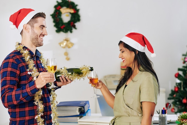 Joyeux jeunes gens d'affaires buvant du champagne lors de la célébration de Noël au bureau