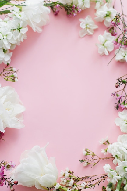 Joyeux jour de la mère et jour de la femme Des fleurs blanches élégantes étendues sur un fond rose espace pour le texte De belles tulipes tendres et des fleurs de printemps cadre modèle de carte de vœux Bannière florale