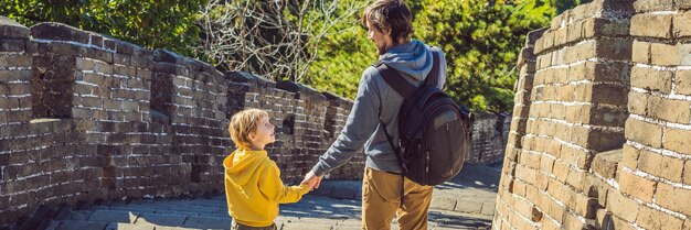 Joyeux joyeux joyeux touristes papa et fils à la grande muraille de chine s'amusant en voyage souriant