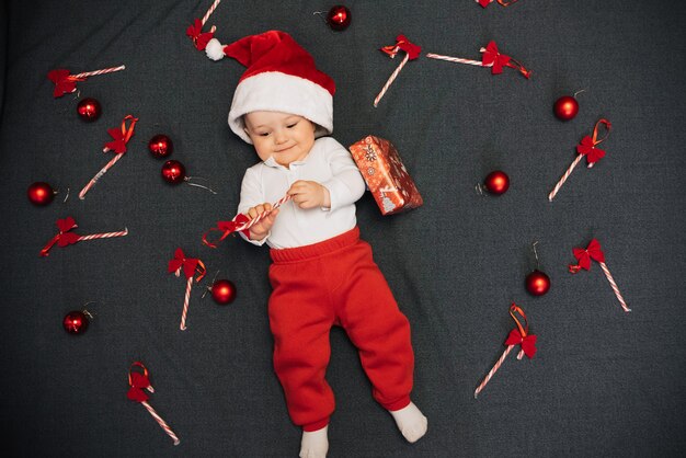 Joyeux joyeux petit garçon au chapeau de père Noël souriant parmi les cannes de bonbon de Noël