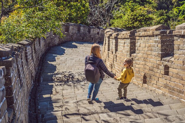 Joyeux joyeux touristes joyeux maman et fils à la grande muraille de chine s'amusant en voyage souriant