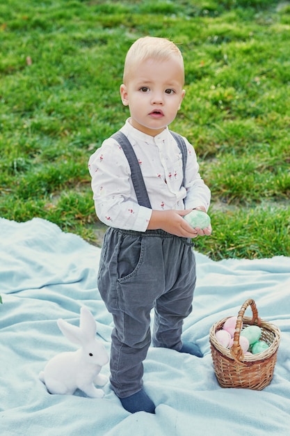 Joyeux lapin de Pâques. Enfant s'amusant en plein air. Enfant jouant avec des oeufs et du lapin sur l'herbe verte.