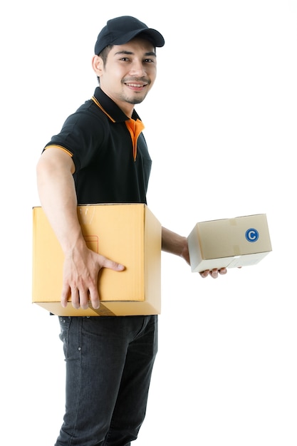 Un Joyeux Livreur Asiatique Tient Des Colis Dans Chaque Main, Sourit à La Caméra. Portrait En Studio D'un Gars De Messagerie En Uniforme Noir Sur Fond Blanc Isolé. Concept D'entreprise De Commerce électronique.