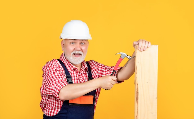 Joyeux menuisier homme âgé en casque sur fond jaune