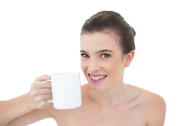 Joyeux modèle aux cheveux brun naturel tenant une tasse de café