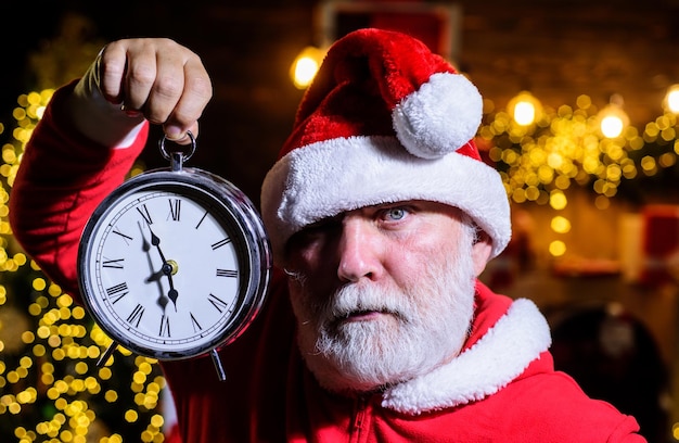 Photo joyeux noël et bonne année au père noël avec réveil le père noël célèbre le noël et le nouvel an