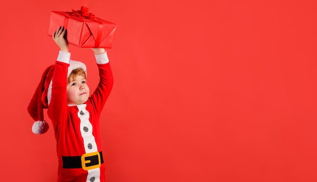 Joyeux Noël et bonne année à l'enfant souriant en costume de Père Noël avec une boîte de cadeaux de Noël nouvelle