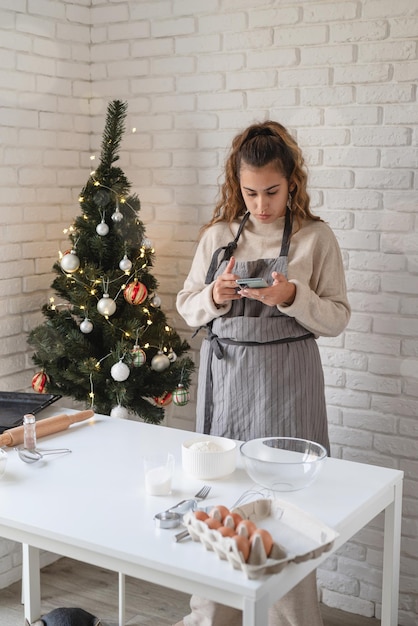 Joyeux Noel et bonne année. Femme souriante dans la cuisine préparant des biscuits de Noël, à la recherche de la recette